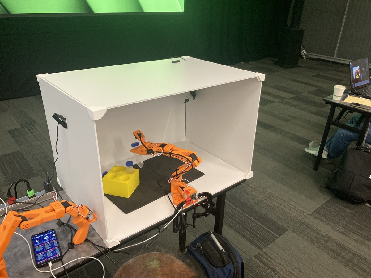 Our workshop station — SO-101 robot arm inside the lightbox with vials and yellow rack